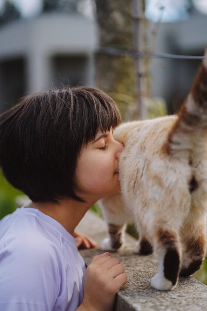 A young girl affectionately interacting with a cat in a rural outdoor setting.